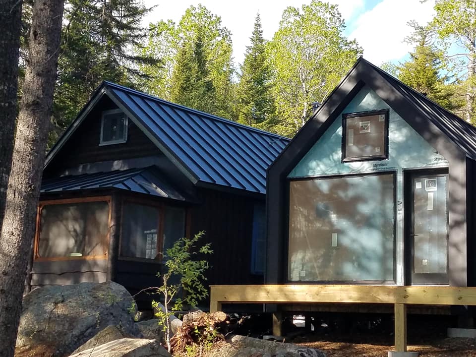 Back seam metal roofing as siding on house in woods