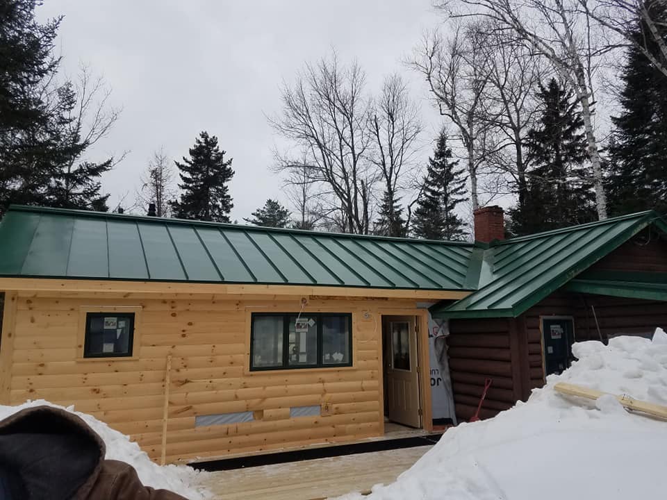 Vibrant green seam metal roofing on pine log cabin