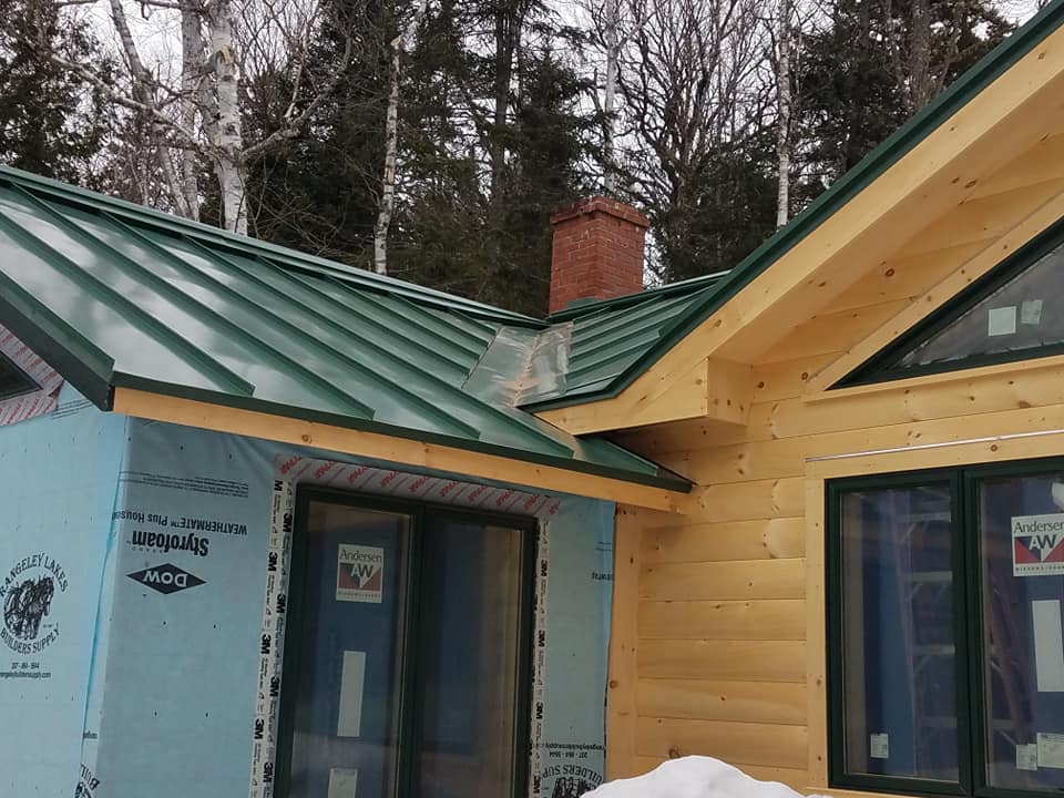 Vibrant green seam metal roofing on pine log cabin